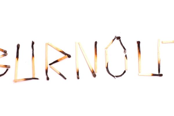 Ausgebrannte Streichhölzer formen das Wort Burnout: Symbol für Erschöpfung und mentale Überlastung.