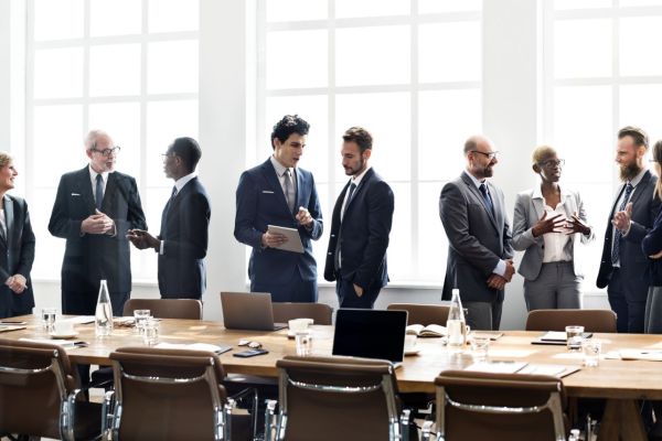 Strategiesitzung eines Teams. Unternehmer im Anzug stehen um einen Tisch herum. 