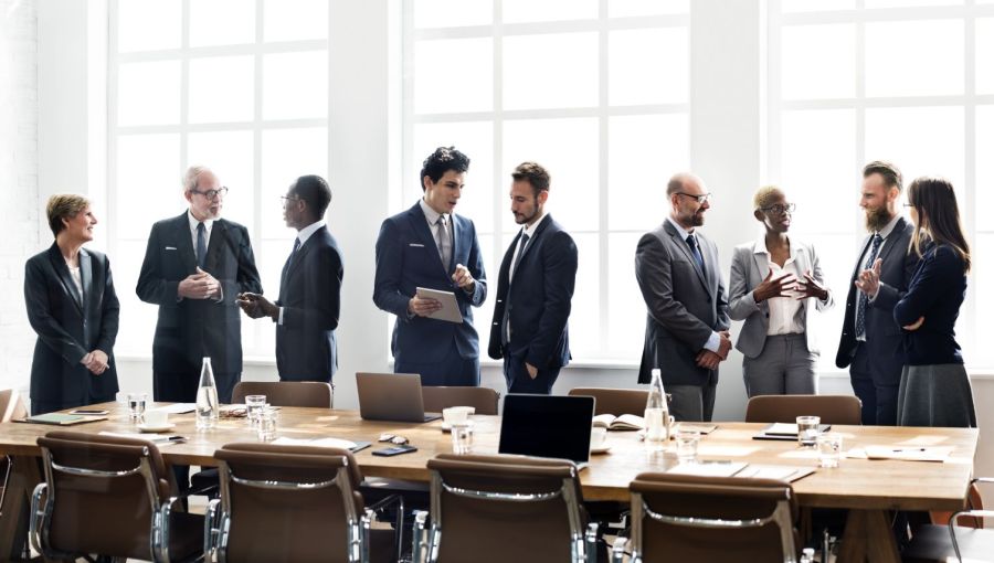 Strategiesitzung eines Teams. Unternehmer im Anzug stehen um einen Tisch herum. 