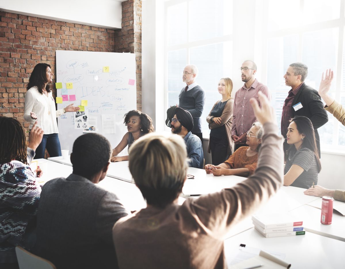 Diverse Projektgruppe bei einem interaktiven Meeting mit Whiteboard und Diskussion – Beispiel für Teamkommunikation.